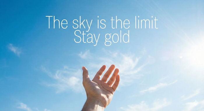 Hand reaching for the sky with positive phrases.